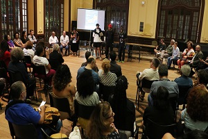 Foto de participantes em semi-círculo, com destaque para pessoas que falam no momento