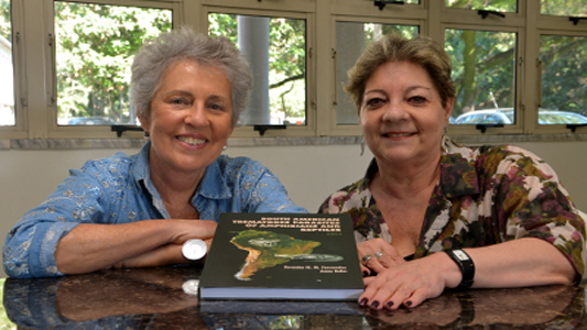 Imagem de duas mulheres segurando o livro lançado pelo IOC