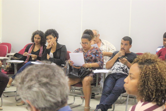 Grupo de pessoas reunidas em círculo em sala de aula debatendo um tema 