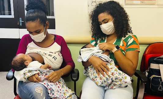 Duas mães sentadas amamentando seus bebês