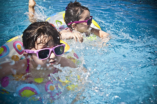 Crianças com óculos escuros mergulhando na piscina
