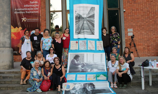 Participantes da exposição sentados na entrada da biblioteca