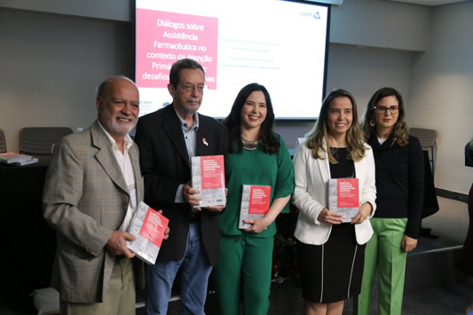 Cinco integrantes do grupo posam para foto segurando o livro