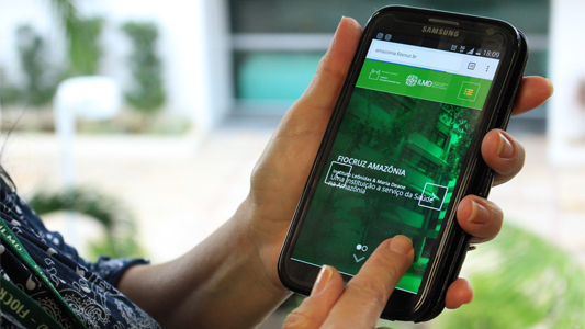 Mulher acessando o site da Fiocruz Amazônia pelo celular