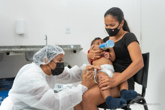 Bebê tomando vacina no colo da mãe