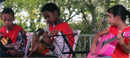 Três crianças tocando violão