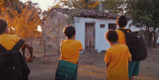 Três crianças em frente a uma casa
