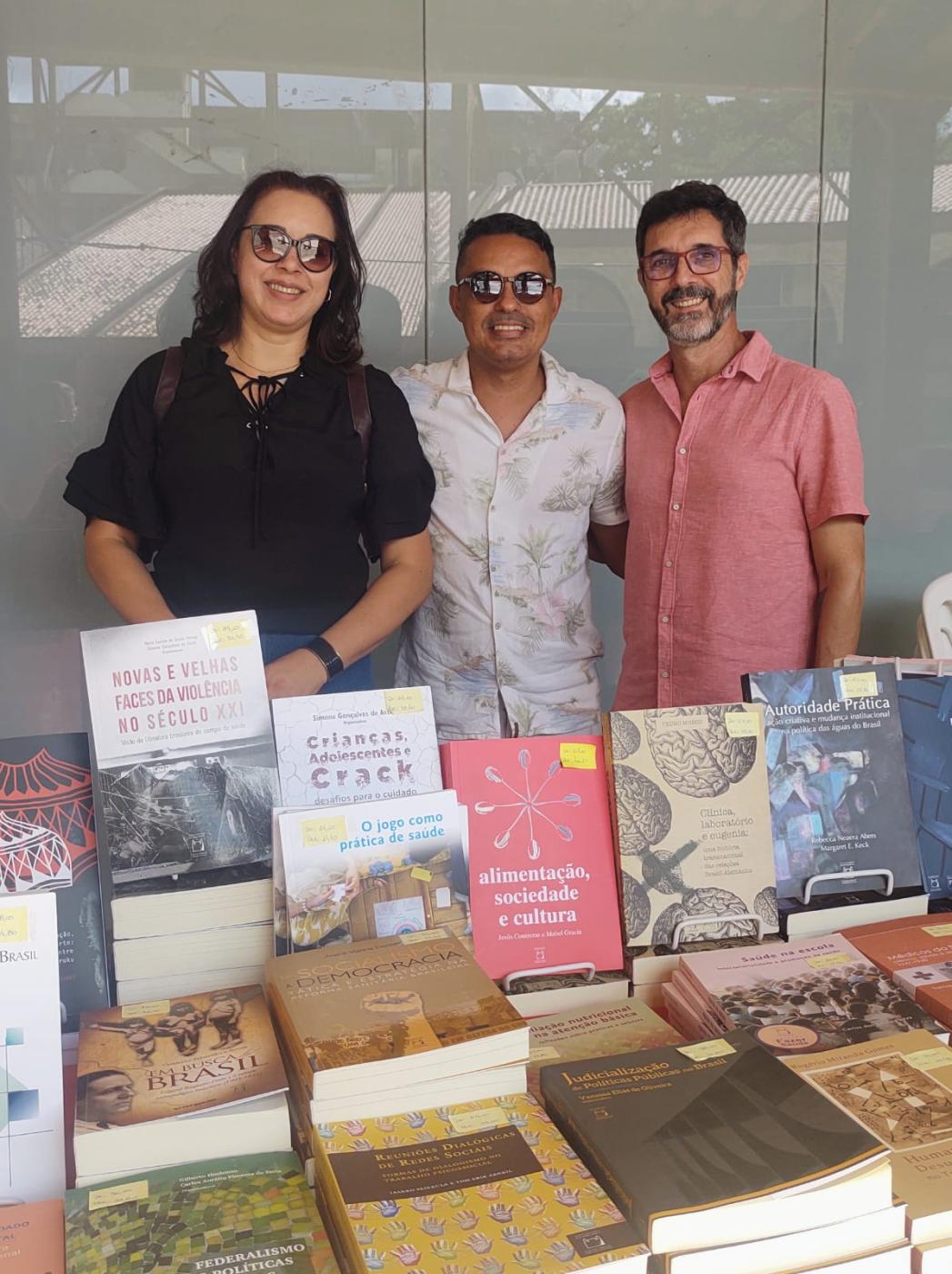 Membros da Abeu (a presidente, o diretor financeiro e o secretário executivo) posam com os livros da Editora Fiocruz.
