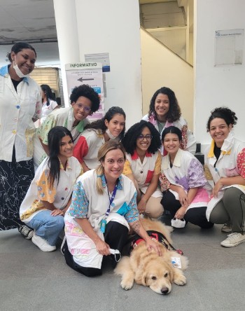 Equipe de estagiárias e residentes com a colaboradora canina, Flor.
