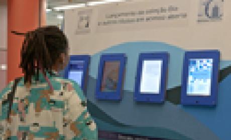 Foto: Raquel Portugal Mulher vendo telas de computador colocadas na parede como um quadro