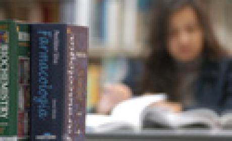 Foto: Paulo Rodino/Fiocruz Imagem de mulher lendo, ao fundo, com lombadas de livro em primeiro plano