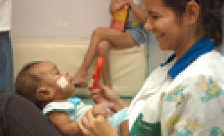 Foto: Instituto Fernandes Figueira/ Divulgação Mulher de uniforme brinca com uma criança pequena