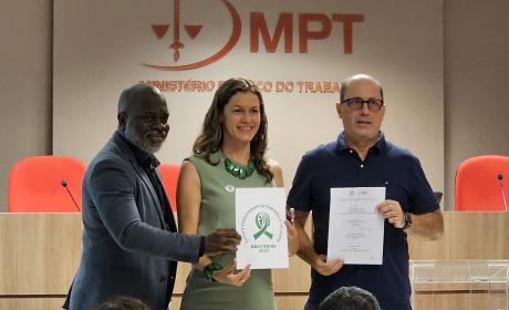 Foto com três pessoas mostrando um documento relacionado ao Abril Verde.