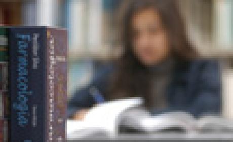 Aos fundos e desfocado, menina estuda em biblioteca