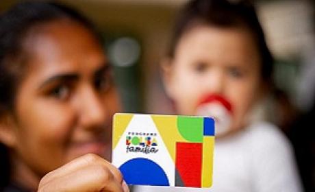 Imagem: divulgação Mulher segurando um cartão do bolsa família com bebê no colo