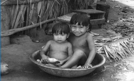 Duas crianças bem pequenas brincando em uma bacia com água