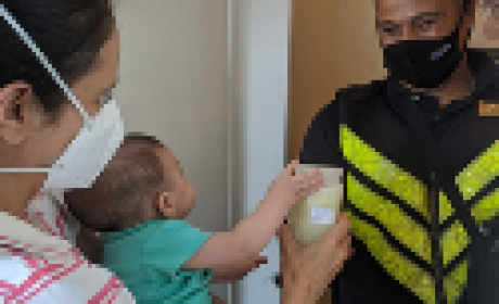 Imagem: IFF Profissional de saúde entregando um pote de leite doado a uma mãe com bebê no colo