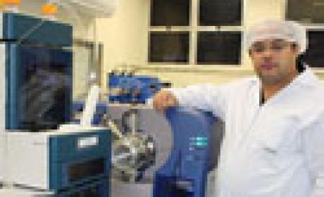 Douglas Pereira e o espectômetro de massas. Imagem: Clarisse Castro Imagem de homem ao lado de equipamento de laboratório
