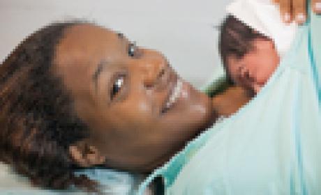 Reprodução Mulher sorri com bebê recém-nascido sobre o seio