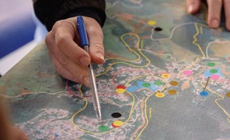 Mãos sobre um mapa indicando pontos com a ponta da caneta