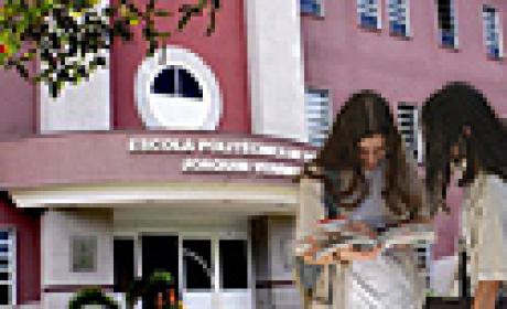 Duas estudantes conferindo um papel em frente à fachada do Politécnico