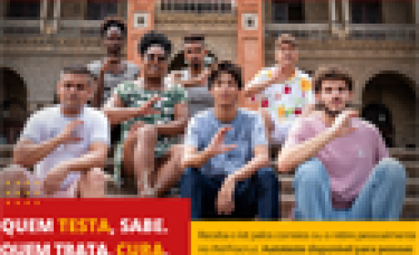 Sete pessoas sentadas em frente ao Castelo da Fiocruz fazendo um C com a mão