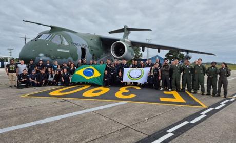Grupo de integrantes da comitiva reunidos em frente a um avião