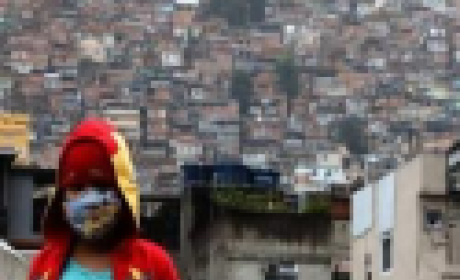 Menino de máscara na entrada de uma favela