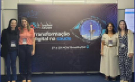 Quatro mulheres brancas posam para foto ao lado de cartaz transformação digital em saúde na 6ª Feira de Soluções para a Saúde 