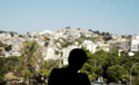 Silhueta de pessoa com favela ao fundo