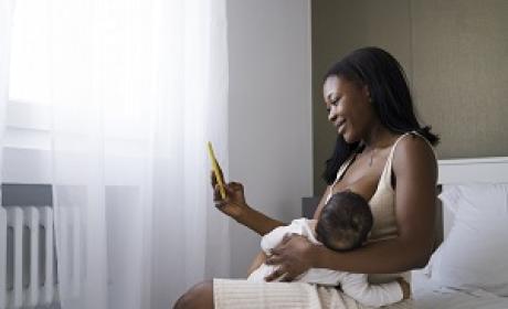 Mulher negra sorri com bebê no colo