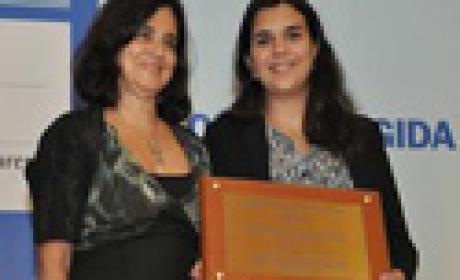 Nísia Trindade e Virgínia Valiate Gonzalez durante entrega do prêmio. Foto: Folha Dirigida Imagem de duas mulheres, na qual uma segura uma placa de homenagem