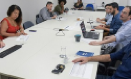 Participantes da reunião sentados ao redor de uma mesa 