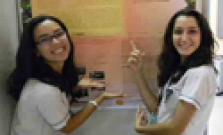 Julia Maia e Maria Carolina Marins fazem iniciação científica no Provoc. Acervo EPSJV Imagem de duas meninas apontando banner
