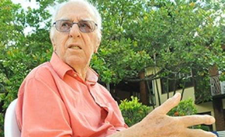 Luis Rey sentado em uma cadeira em um jardim