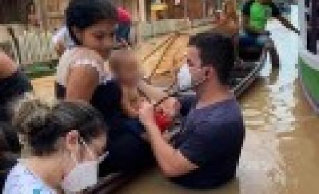 Foto: Lucas Melo Médico no Acre atendendo uma criança que está dentro de uma canoa com a água na cintura