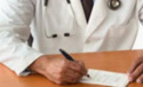 Crédito: Informe Ensp Foto enquadra tronco com jaleco médico e mão assinando prontuário