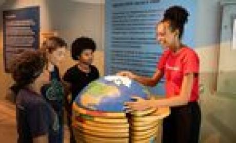 Professora mostra mapa-múndi para um grupo de crianças 