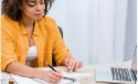 Imagem: IFF Mulher trabalhando sentada lendo em sua mesa