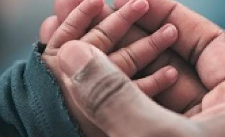 Mulher segura a mão de um bebê 