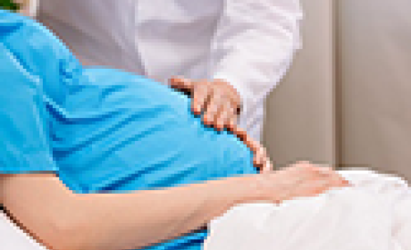 Mulher grávida deitada na cama de hospital e médico examina sua barriga 