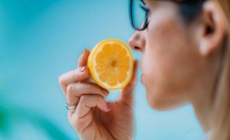 Homem cheirando uma laranja