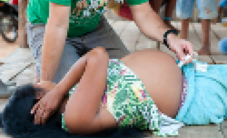 Imagem: Ensp Mulher indígena deitada no chão sendo examinada por um médico