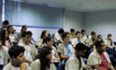 Estudantes de jaleco observam uma aula