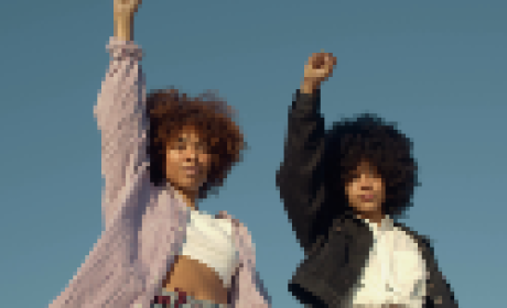 Duas mulheres negras com os punhos fechados e um braço levantado