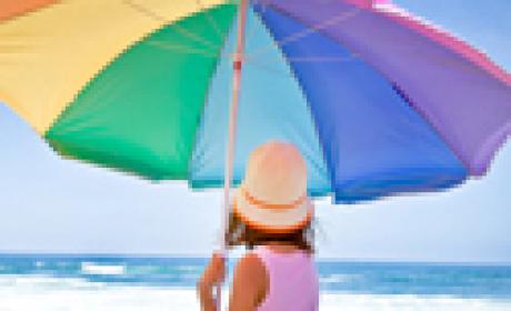 Criança na praia, debaixo de guarda-sol