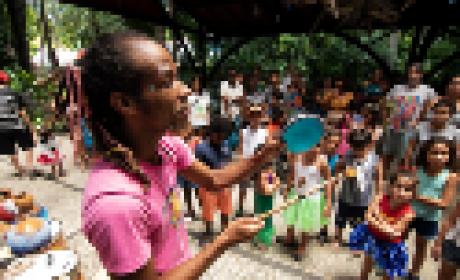 Animador tocando pandeiro para crianças no Campus da Fiocruz em Manguinhos 