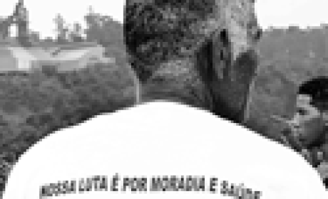 Reprodução Homem de costas com camiseta com os dizeres 'nossa luta é por moradia e saúde'