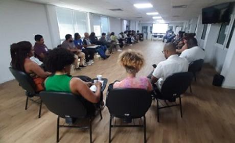 Foto: Divulgação Dezenas de participantes de uma reunião sentados ao redor de uma mesa