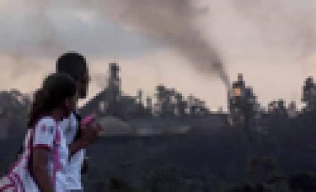 Reprodução de capa da revista Duas meninas com uniforme de escola passam em frente a paisagem de onde fumaça exala